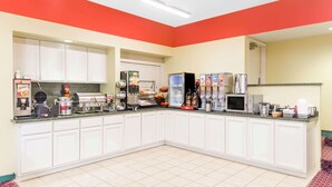 A kitchen with white cabinets, a microwave, a coffee machine, and a refrigerator.