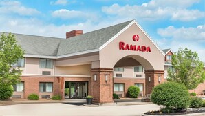 A Ramada hotel with a brick facade, large entrance, and a clear sky.