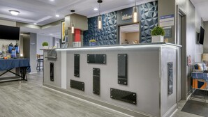 A reception area with a modern design, including a counter with nameplates, a welcome sign, and a digital screen displaying the time. - Best Western The Inn At Rochester Airport (Rochester)