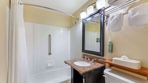 A bathroom with a bathtub, a sink, a mirror, and a towel rack.