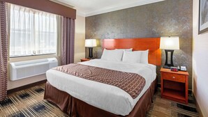 A hotel room with a large bed, two bedside tables with lamps, a window with curtains, and a wall with a bamboo pattern. - Best Western The Inn At Rochester Airport (Rochester)