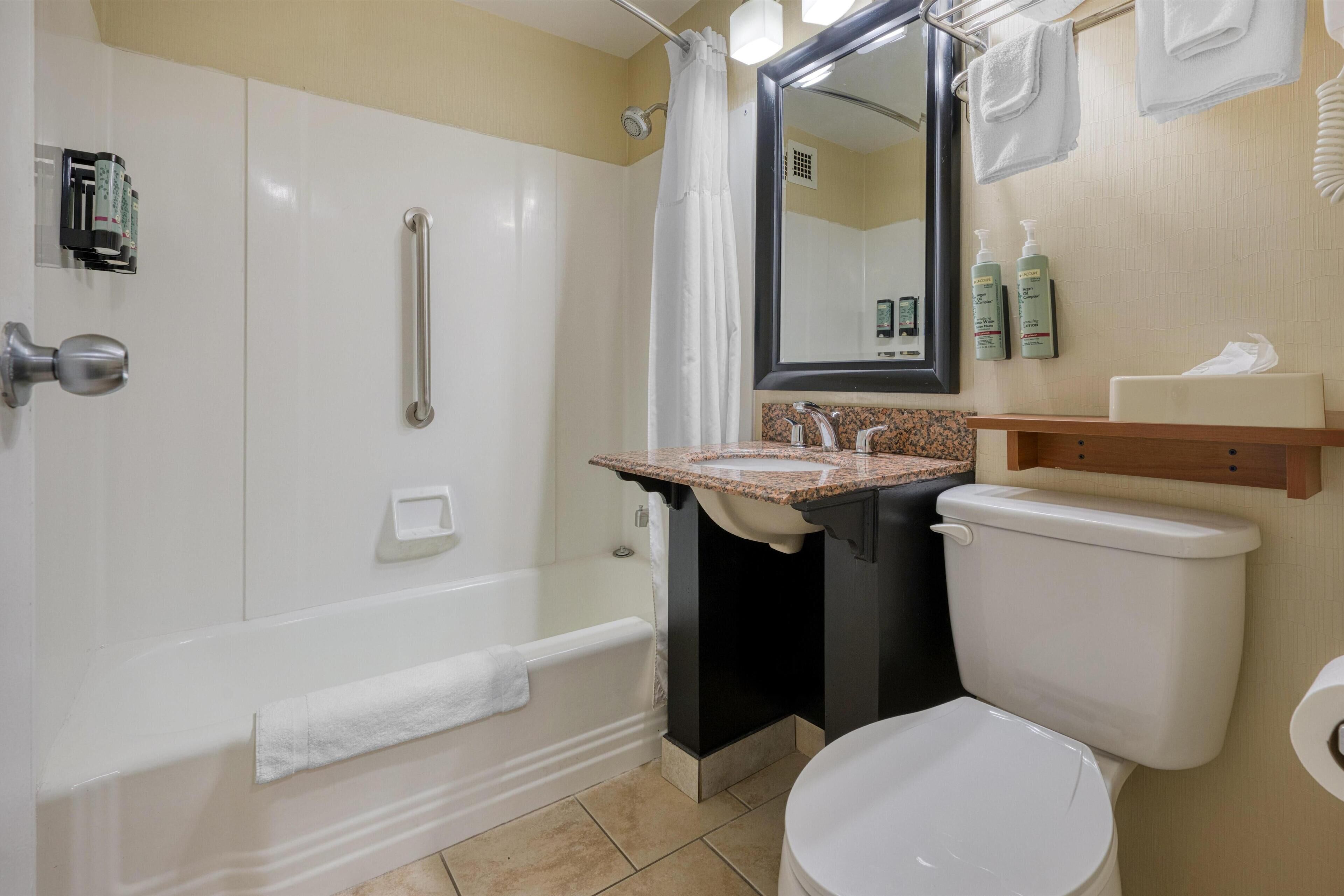 Une salle de bain équipée d’une baignoire, de toilettes, d’un lavabo, d’un miroir et d’un porte-serviettes.