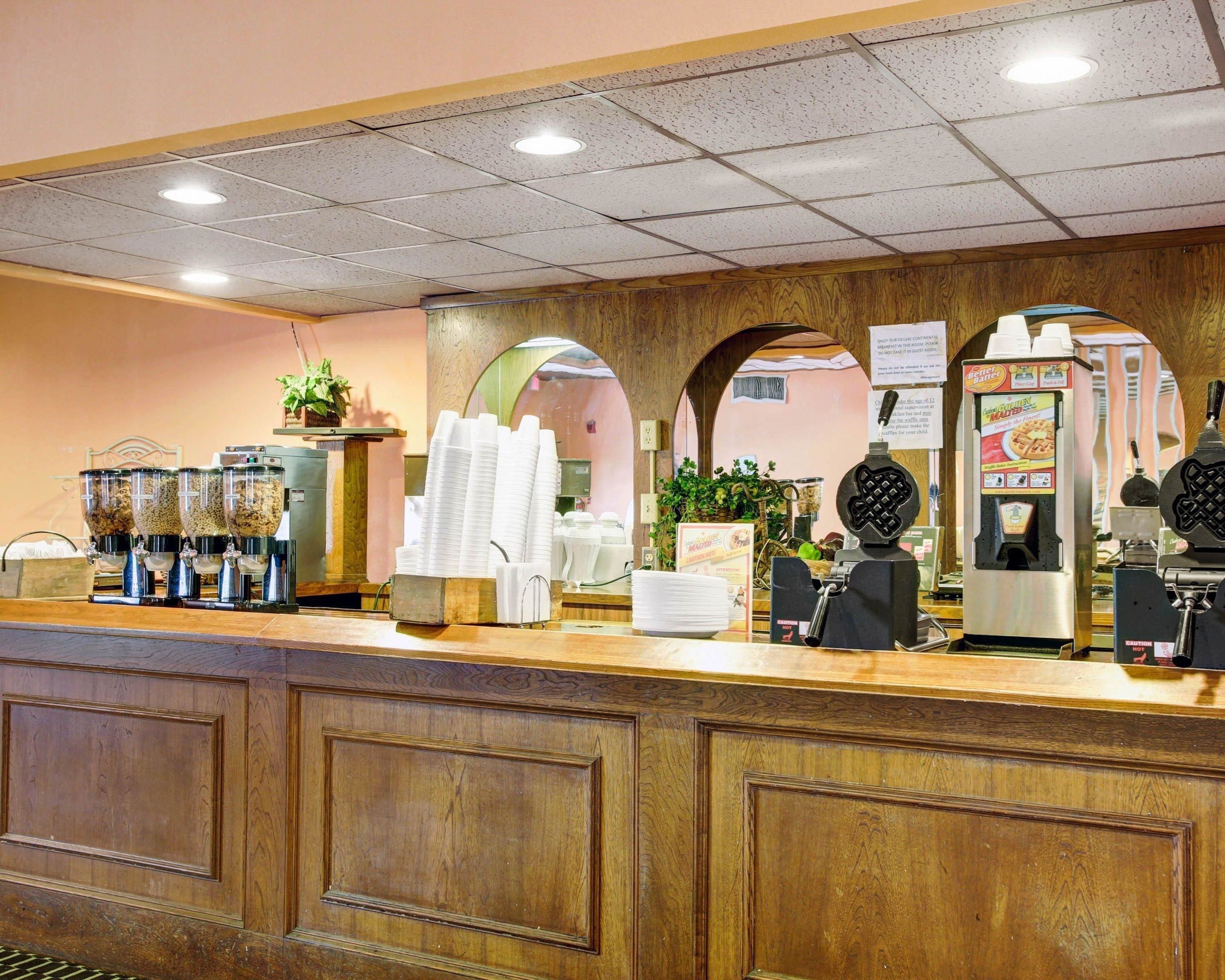 A coffee station with multiple coffee dispensers, a waffle maker, and a menu board.