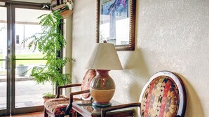 A lobby with a wooden chair, a table with a lamp, and a potted plant. - Rodeway Inn New Braunfels - San Antonio Area (New Braunfels)