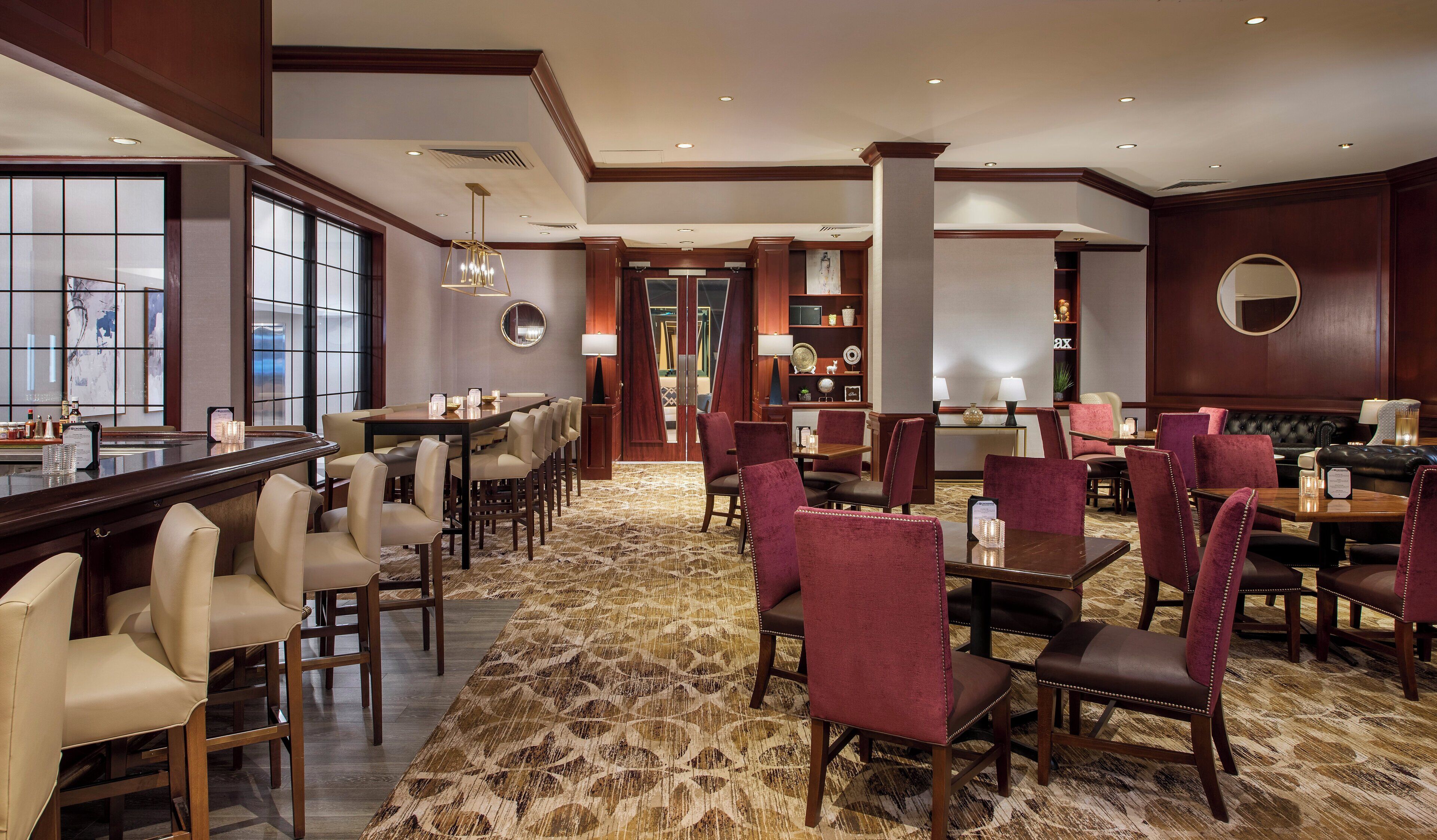 A hotel lobby with a bar area, seating arrangements, and a reception desk.