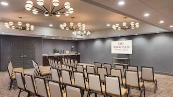 A conference room with rows of chairs, a podium, and a screen displaying the logo 'CROWNE PLAZA PROVIDENCE-WARWICK'.