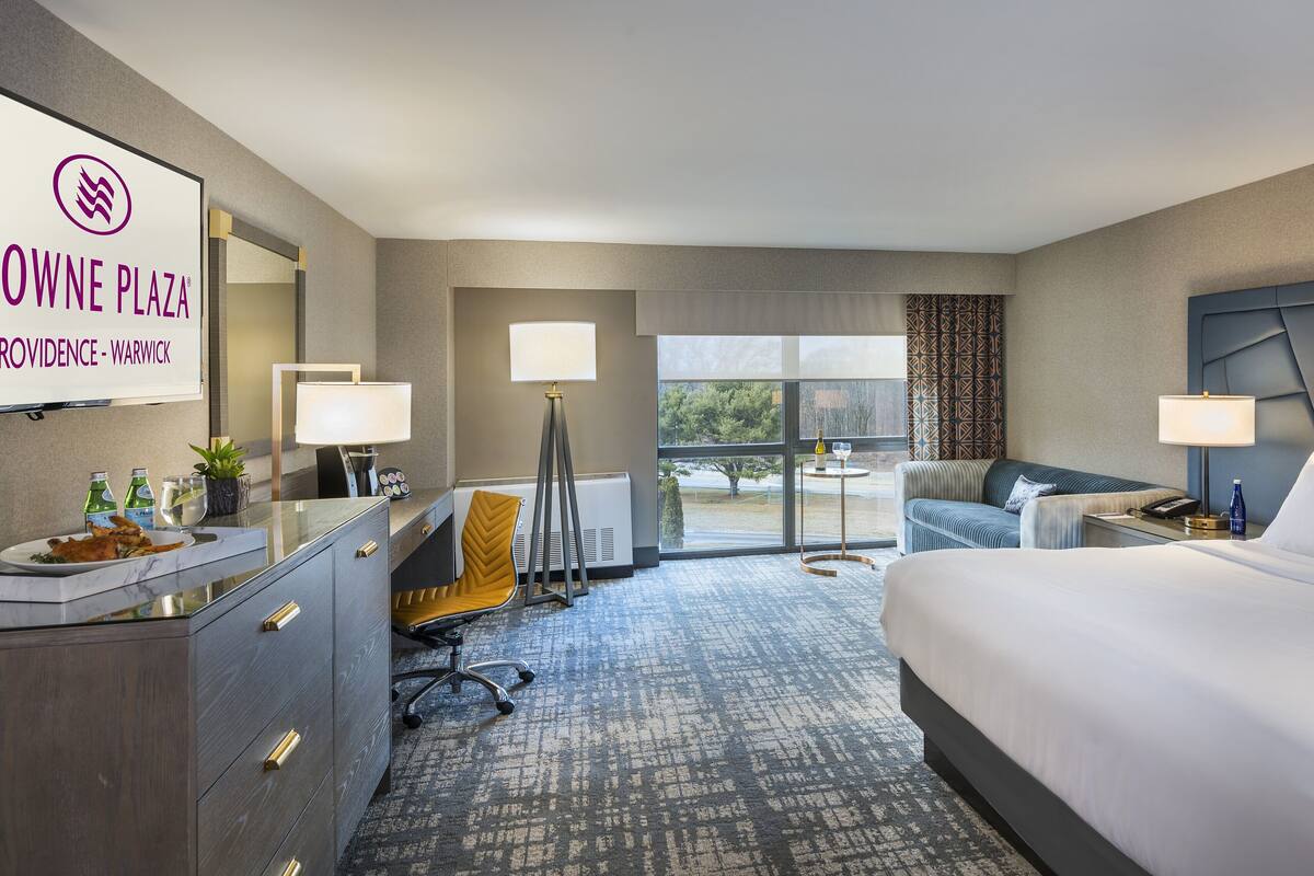 Een hotelkamer met een bed, bureau, stoel en uitzicht op de omgeving.