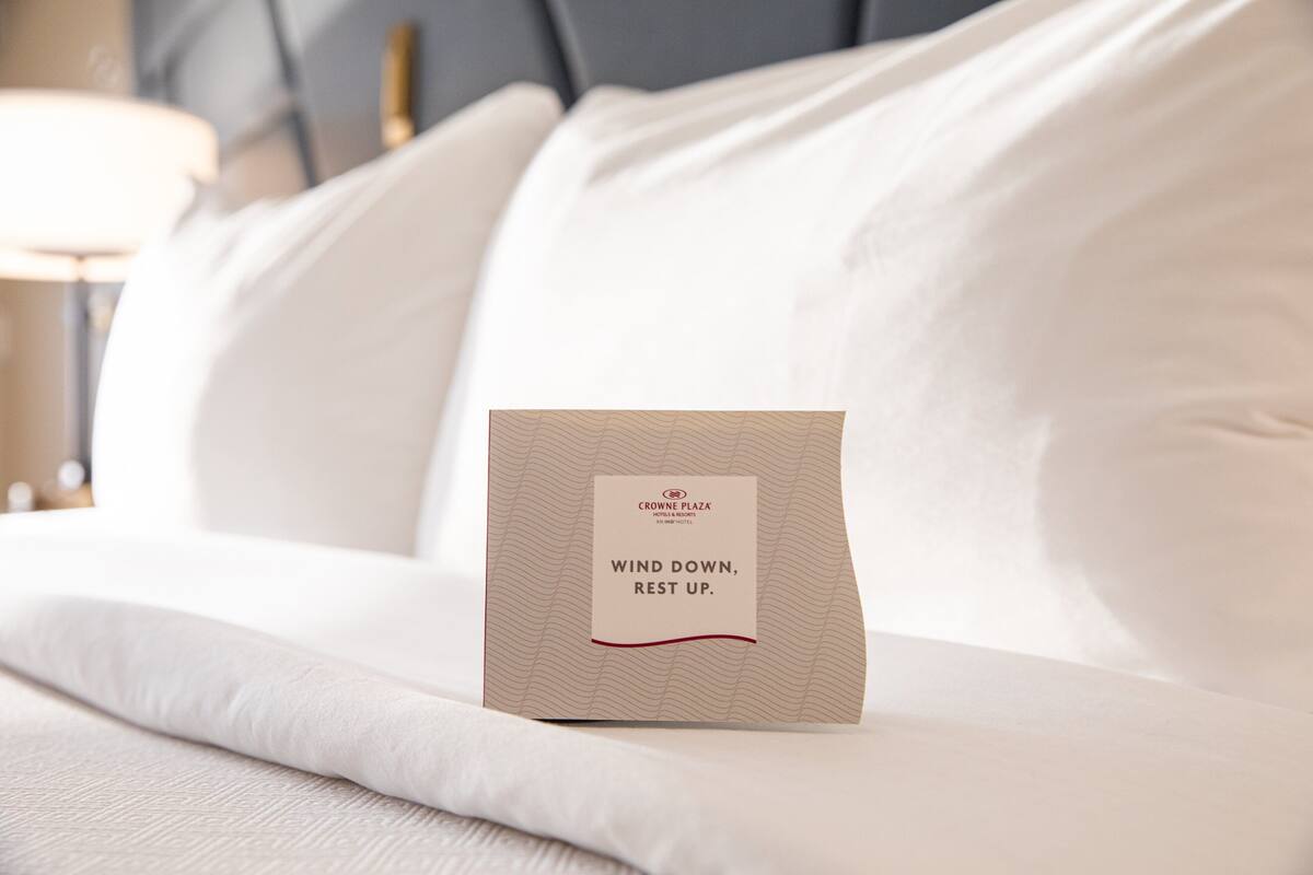 Een net opgemaakt bed met een kussen en een label waarop staat 