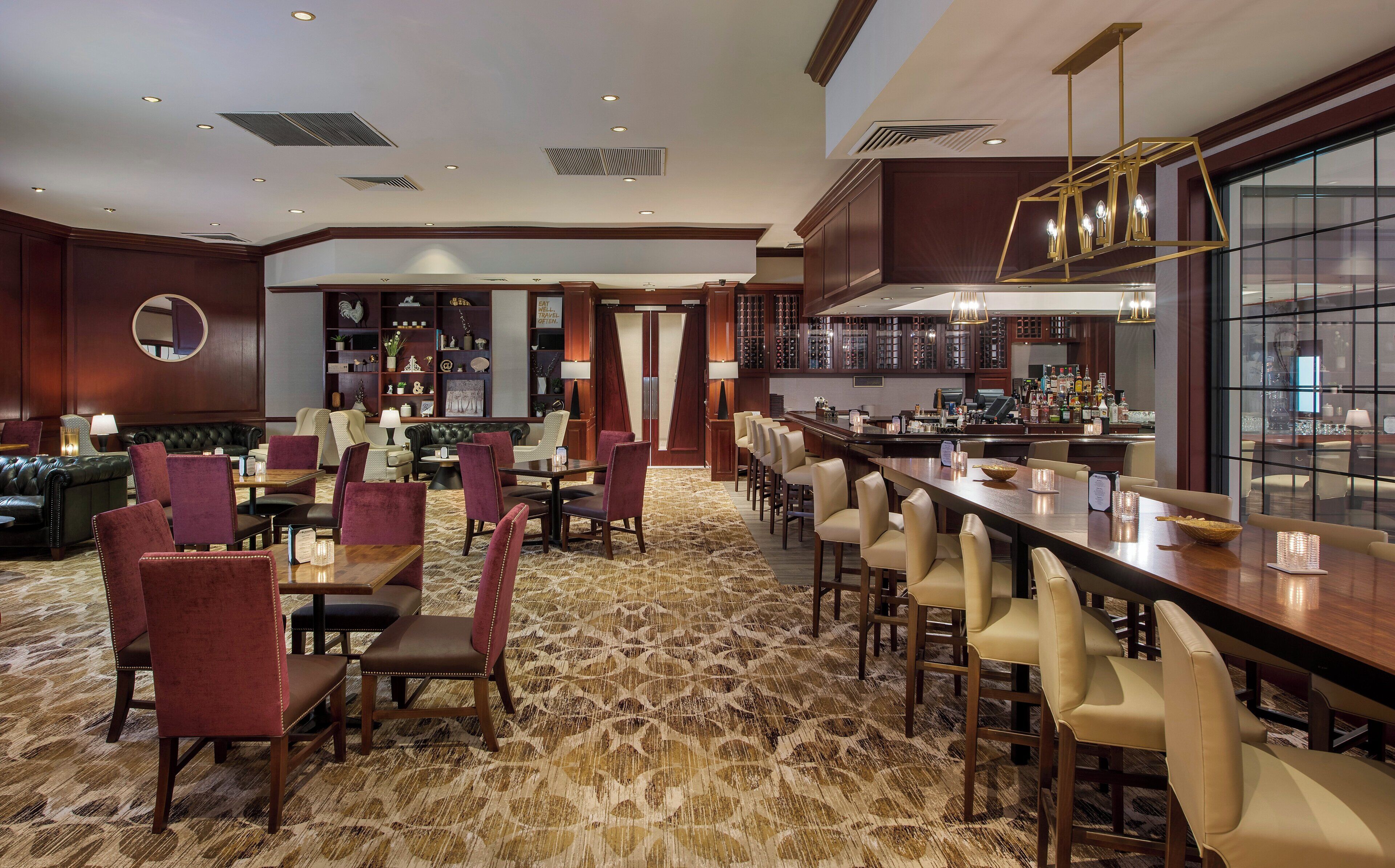 A hotel lobby with a bar area, seating arrangements, and a view of the bar.