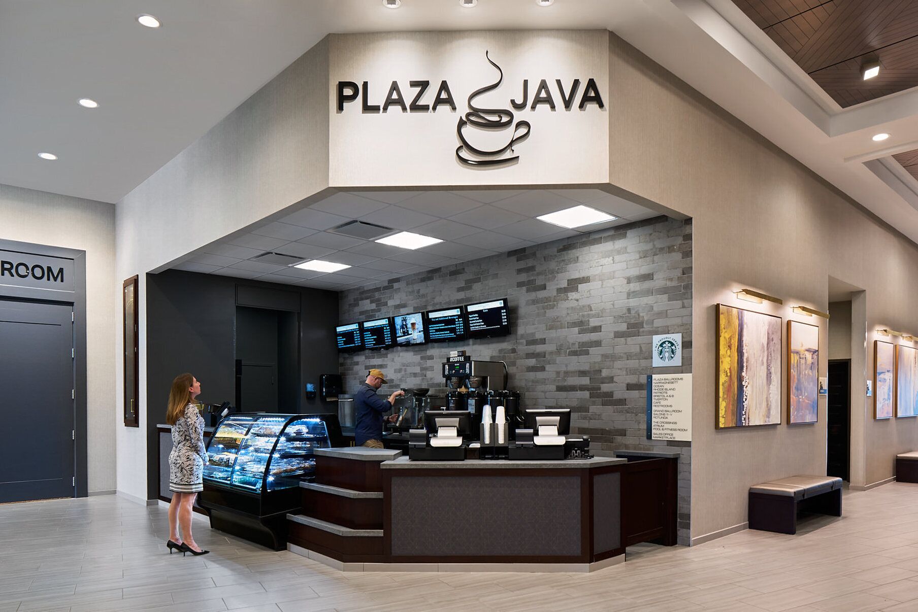 A modern coffee shop named 'Plaza Java' with a digital menu display, a coffee machine, and a glass display case of pastries.