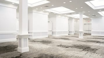 A spacious hotel lobby with high ceilings, skylights, and a patterned carpet.