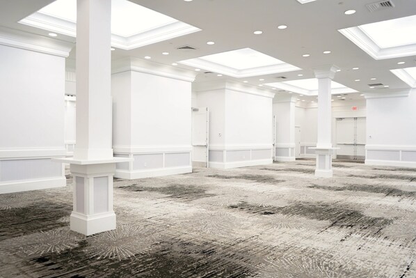 A spacious hotel lobby with high ceilings, skylights, and a patterned carpet.