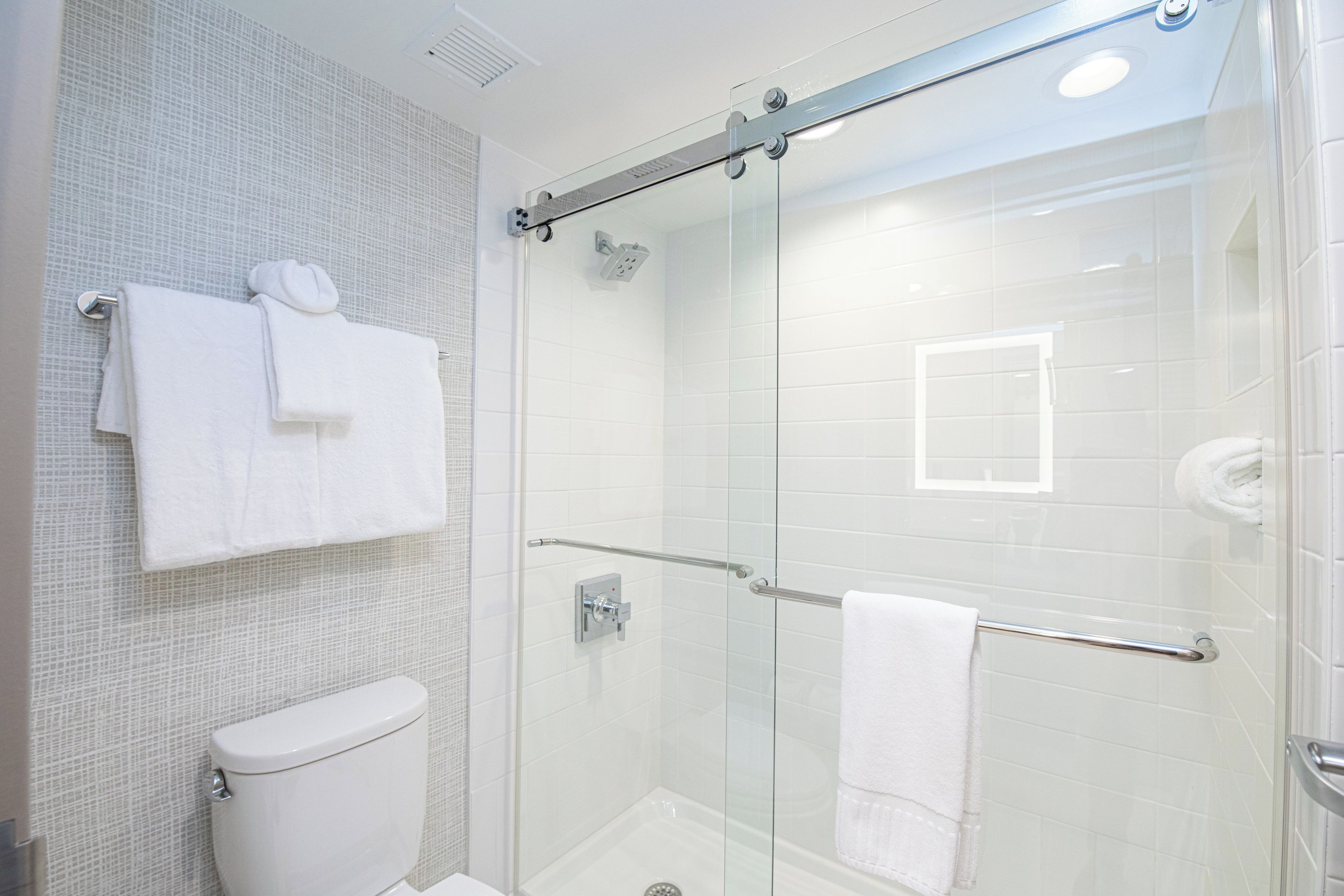 Une salle de bain moderne avec une douche à parois de verre, des toilettes et un porte-serviettes.
