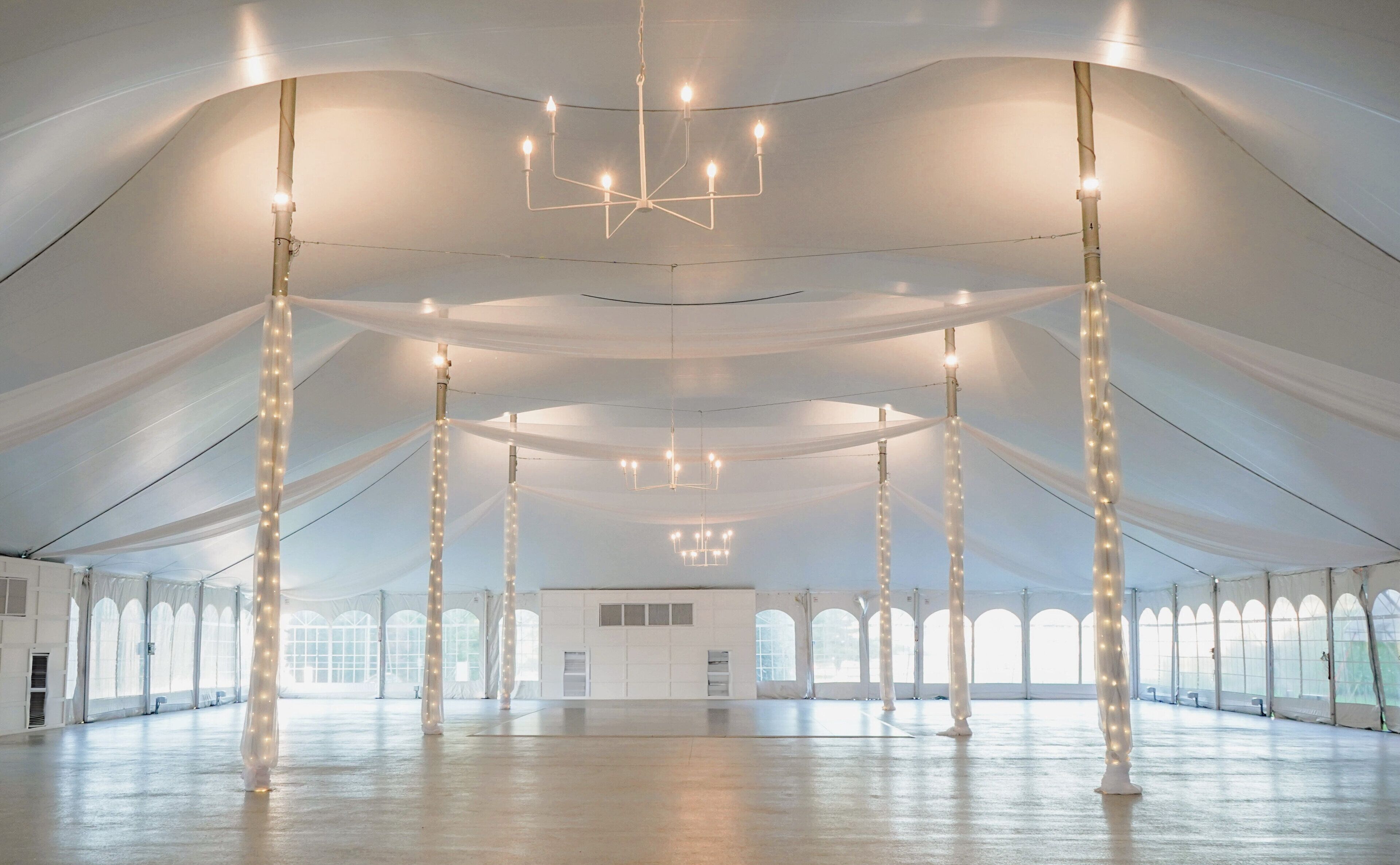 A large, open interior space with high ceilings, multiple columns, and a central chandelier.