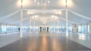 A large, open indoor space with high ceilings, white drapery, and multiple chandeliers.