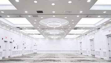Un salón de conferencias amplio y vacío, con techo alto, iluminación empotrada y un candelabro central.