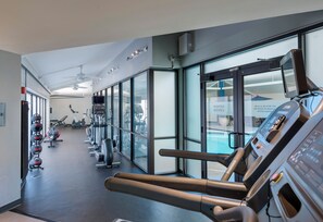 Een fitnessruimte met loopbanden, hometrainers en krachtapparaten.