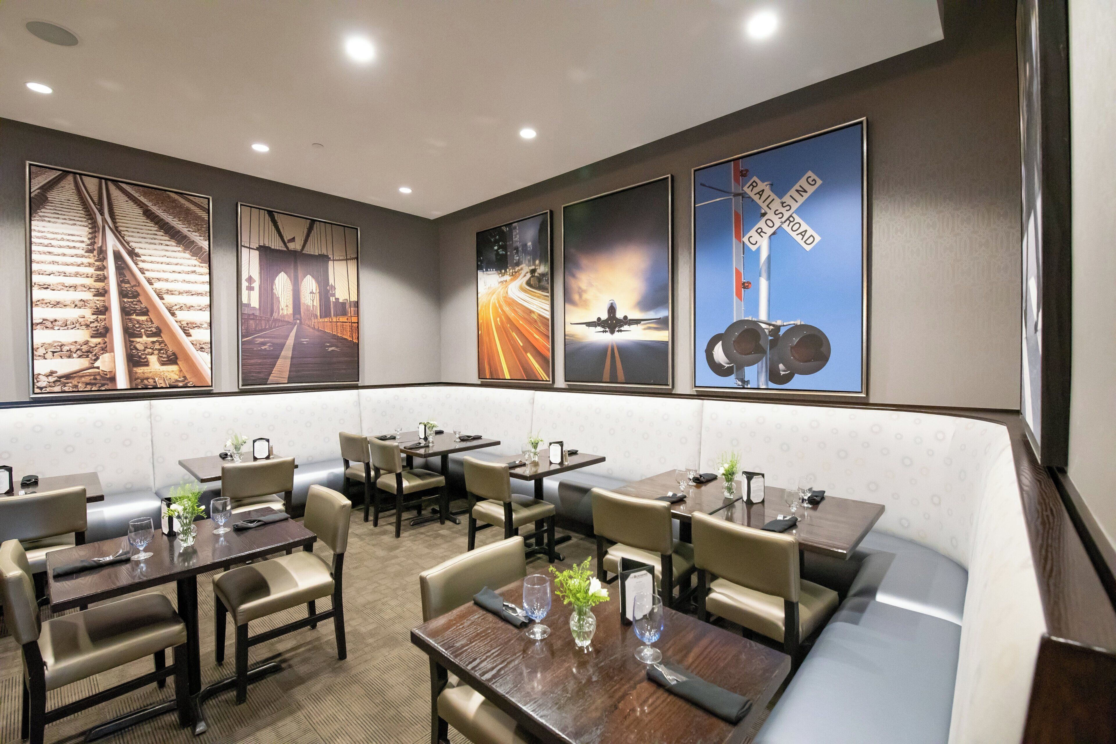 A restaurant with multiple tables and booths, decorated with framed pictures of trains and railroads.