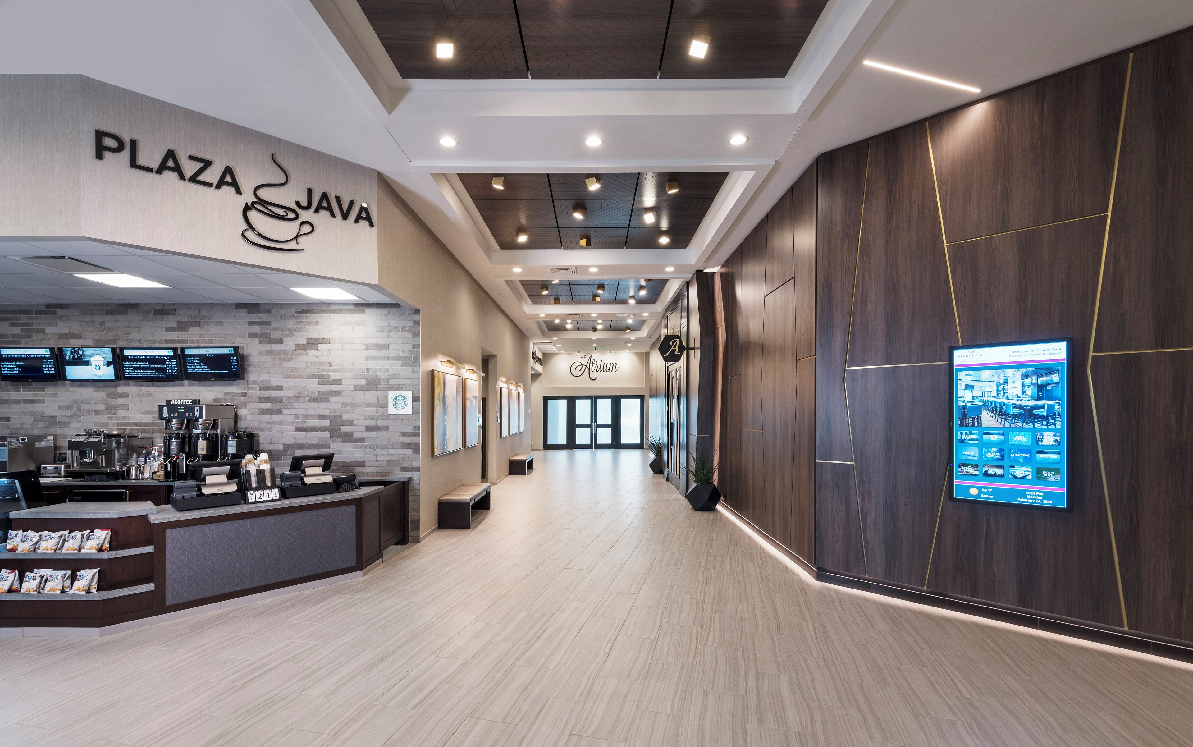 A modern interior with a reception desk, digital menu boards, and a wooden accent wall.