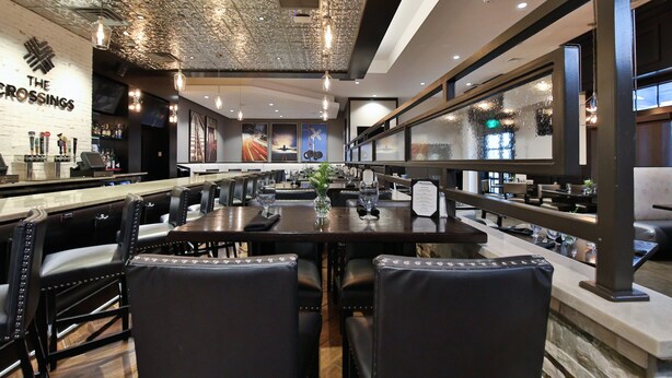 Interior de restaurante con barra, sillas de cuero negro y techo de diseño original.
