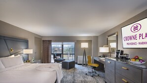 Habitación de hotel con una cama grande, un escritorio con silla, una mesita y ventana con vistas.