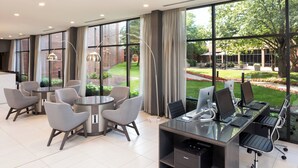 A modern office space with a glass desk, ergonomic chairs, and a view of a landscaped garden. - Delta Hotels by Marriott Minneapolis Northeast (Minneapolis)