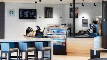A modern coffee shop interior with a counter, seating area, and a display of beverages.