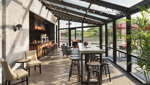 An indoor dining area with a bar, high tables, and bar stools. - Delta Hotels by Marriott Minneapolis Northeast (Minneapolis)
