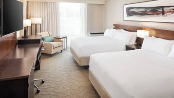 A hotel room with two beds, a TV, a desk, and a chair.