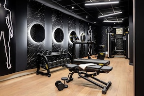 Academia com equipamentos de exercício, paredes de mármore e placa da NYX Hotels.