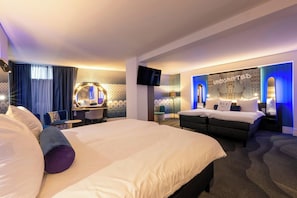 A hotel room with a large bed, a vanity with a mirror, a television, and a wall with a 'UNBURISHED' sign. - NYX Hotel Amsterdam Rembrandt Square (Amsterdam)