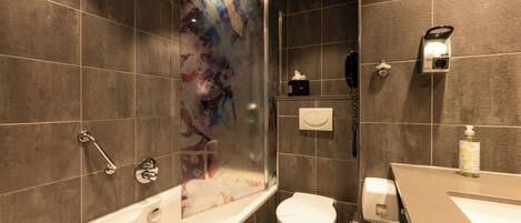 Un baño moderno con bañera, inodoro y zona de ducha.