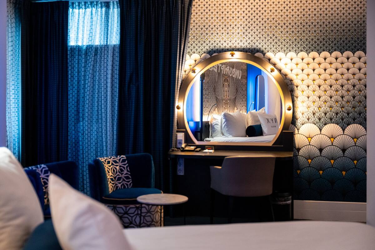 Una habitación de hotel con una cama, un escritorio con espejo, una silla y una mesa redonda.