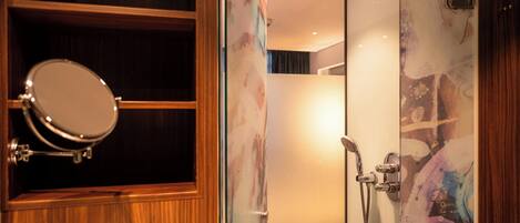 A bathroom with a wooden vanity, a mirror, and a shower with a glass door.