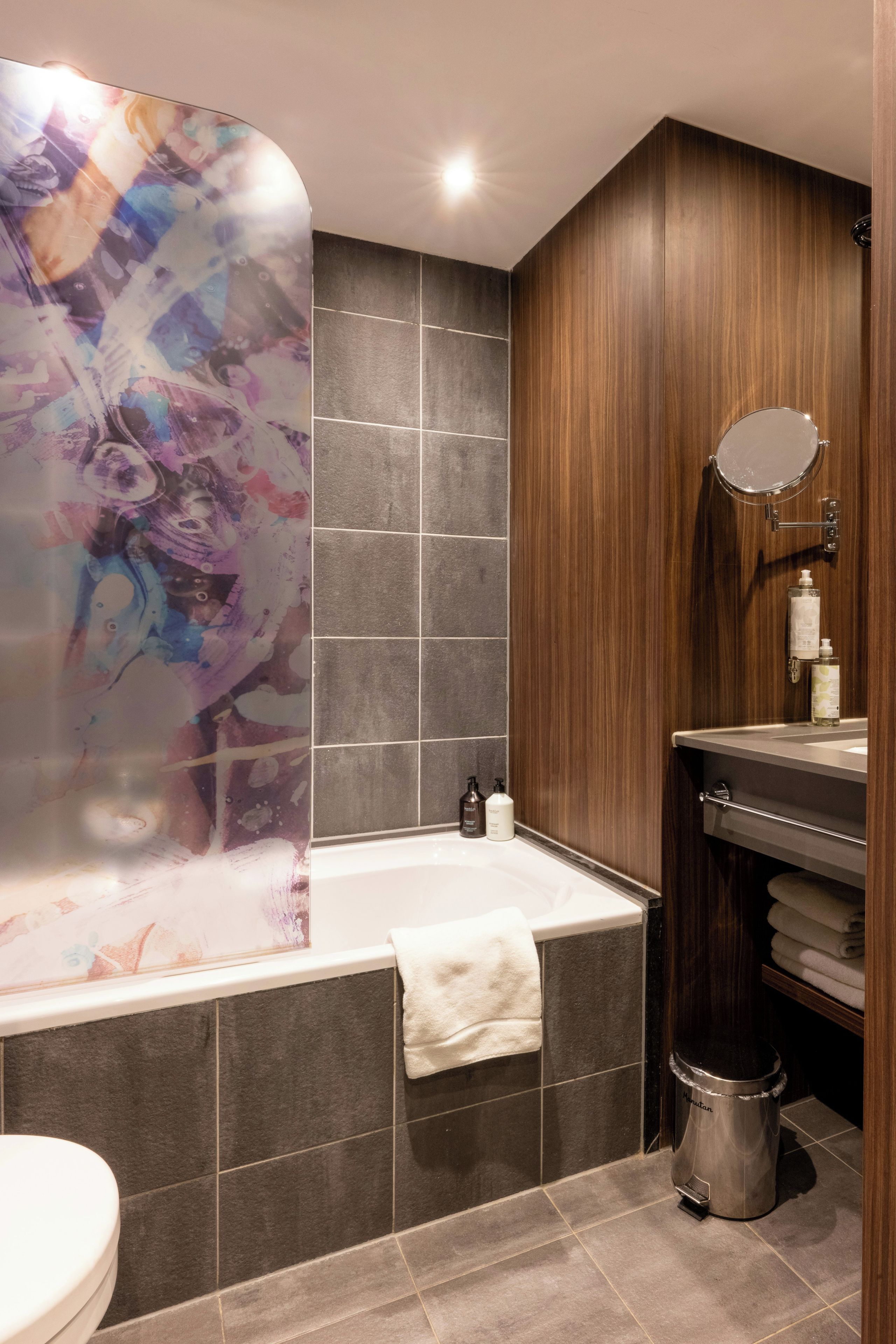 A modern bathroom with a freestanding bathtub, a vanity with a mirror, and a toilet.
