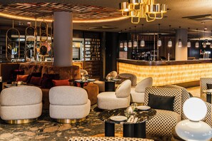 A modern bar area with round seating, a bar counter, and pendant lighting. - NYX Hotel Amsterdam Rembrandt Square (Amsterdam)