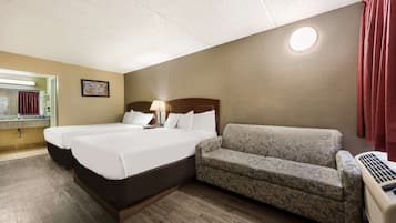 A hotel room with a large bed, a sofa, a mirror, and a heater.