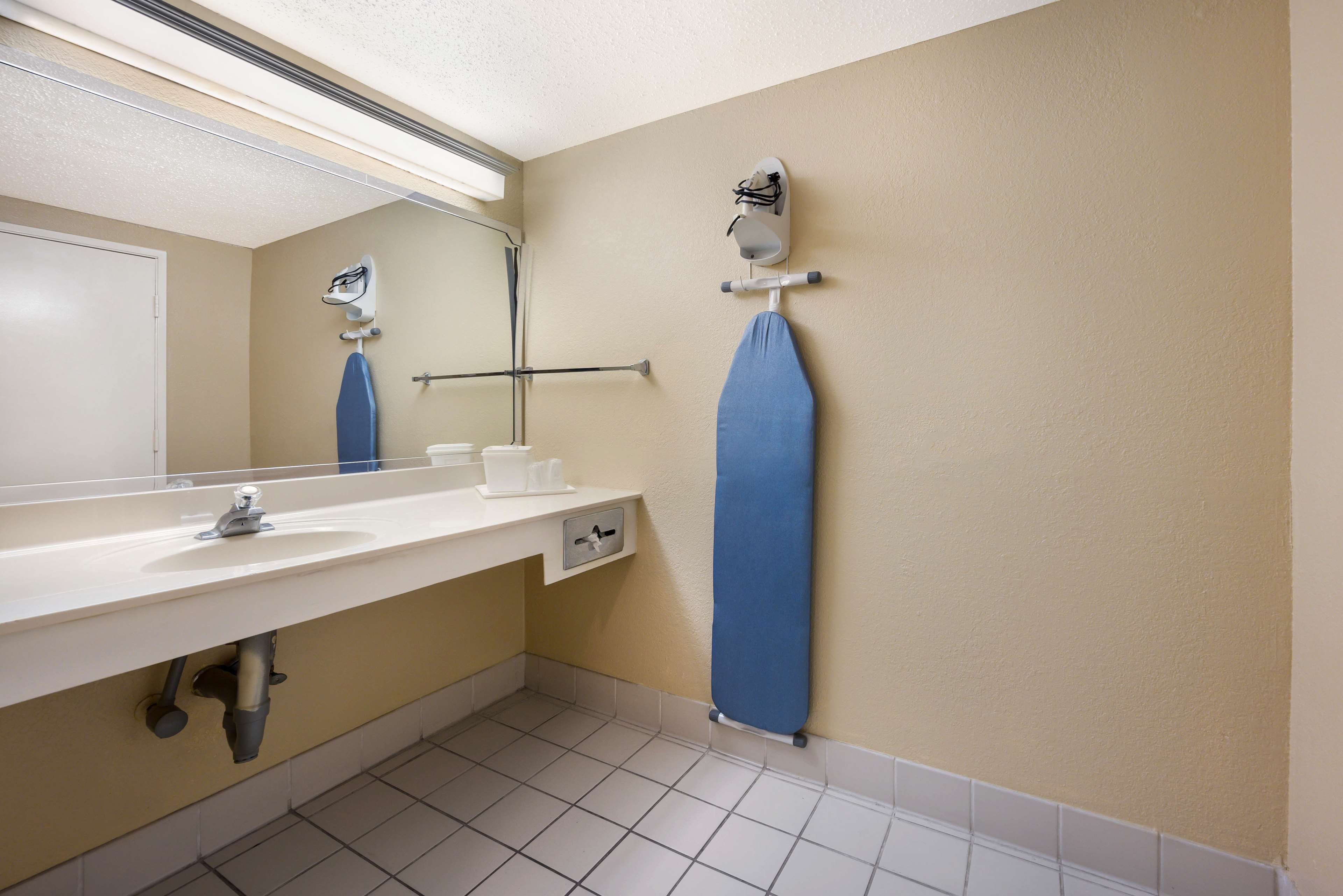 Un baño con lavamanos, espejo, toallero y cabezal de ducha.
