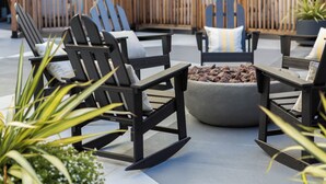 Mobiliario exterior con sillas tipo Adirondack, una fogata y una cerca de bambú.
