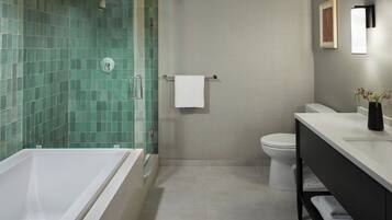 Un baño moderno con ducha envuelta en vidrio, una bañera blanca, un inodoro y un tocador con lavabo y espejo.