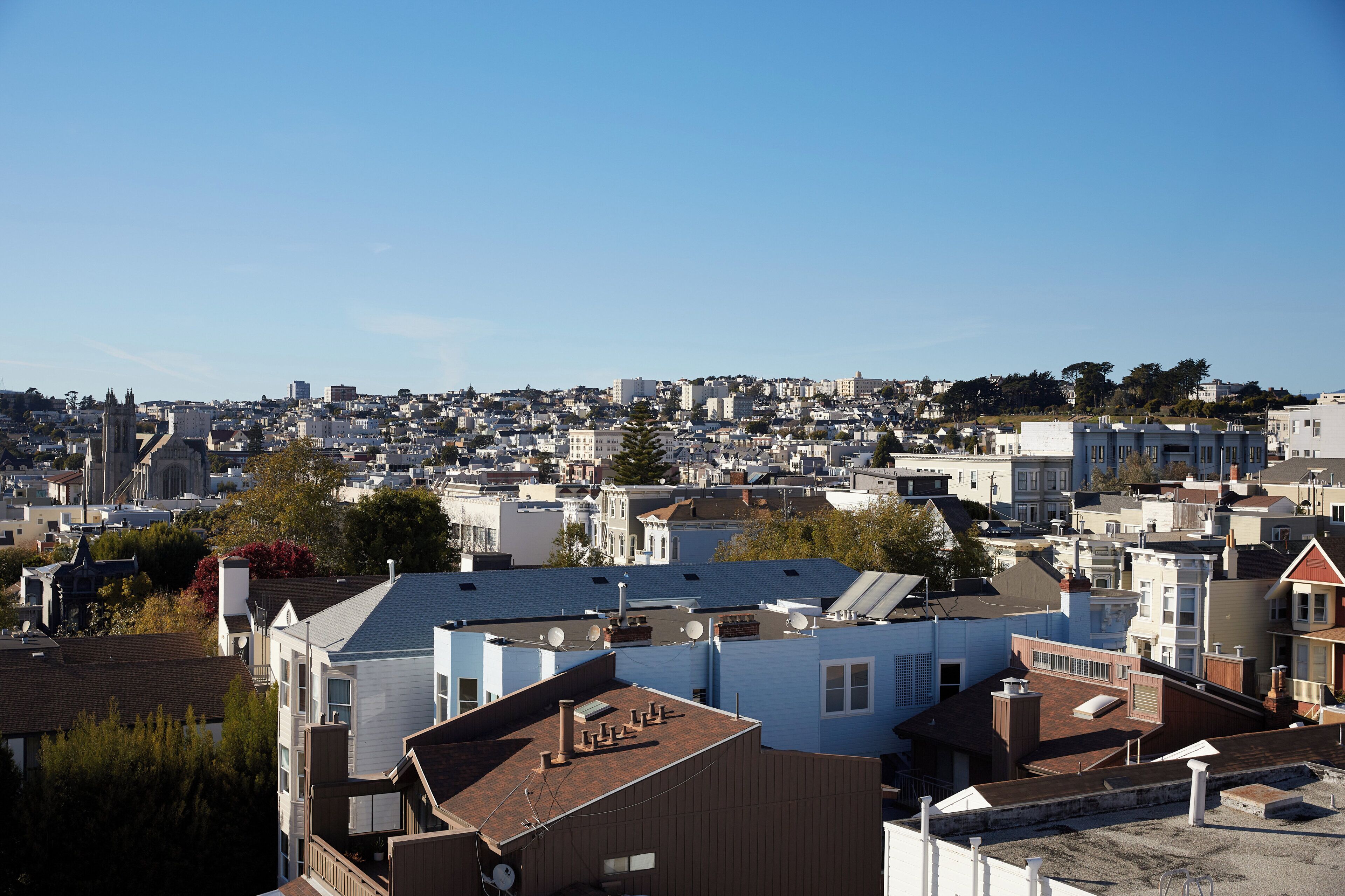 A residential area with various buildings, including houses and apartment complexes, under a clear sky.