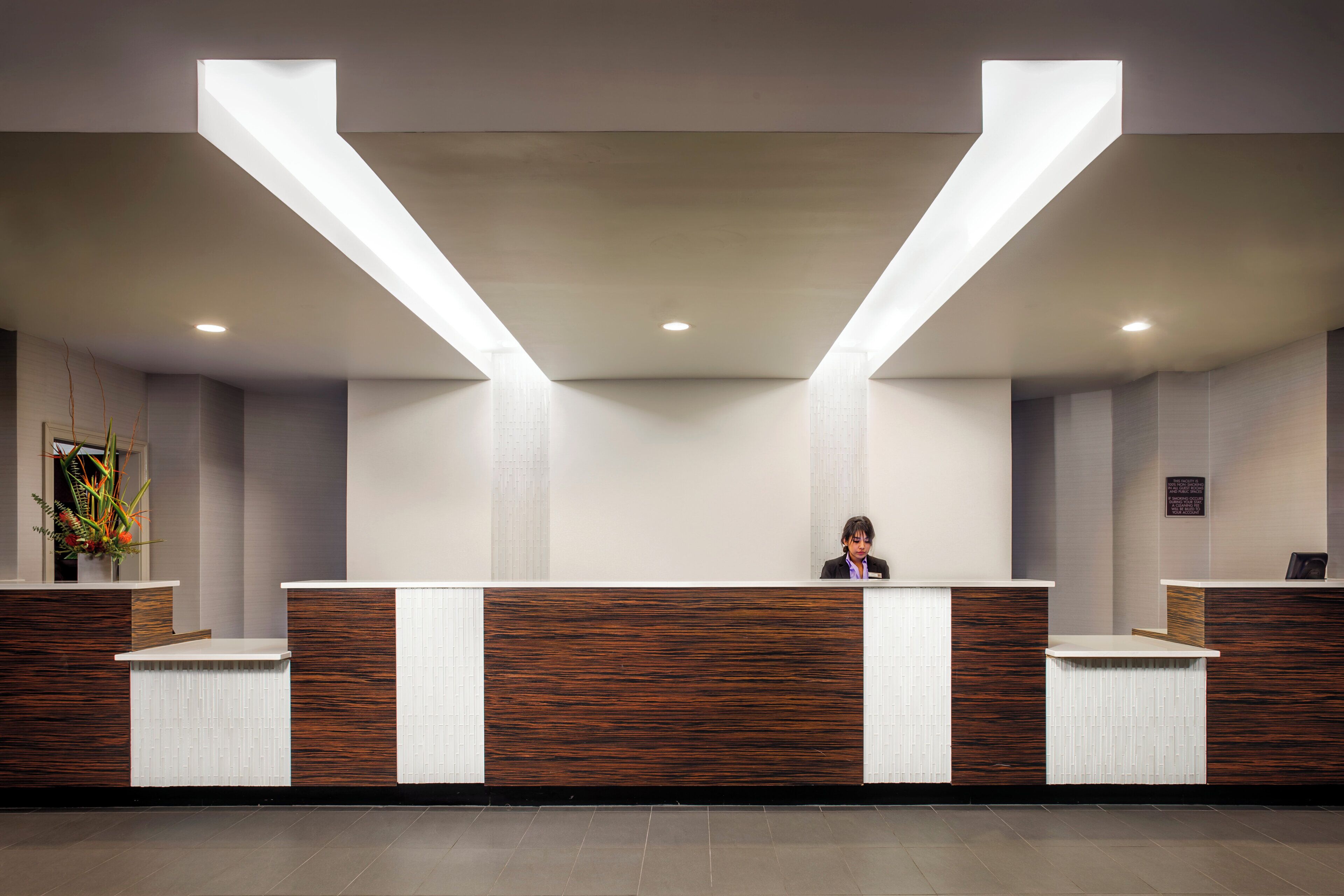 A reception desk with a modern design, featuring a wooden panel and white accents.
