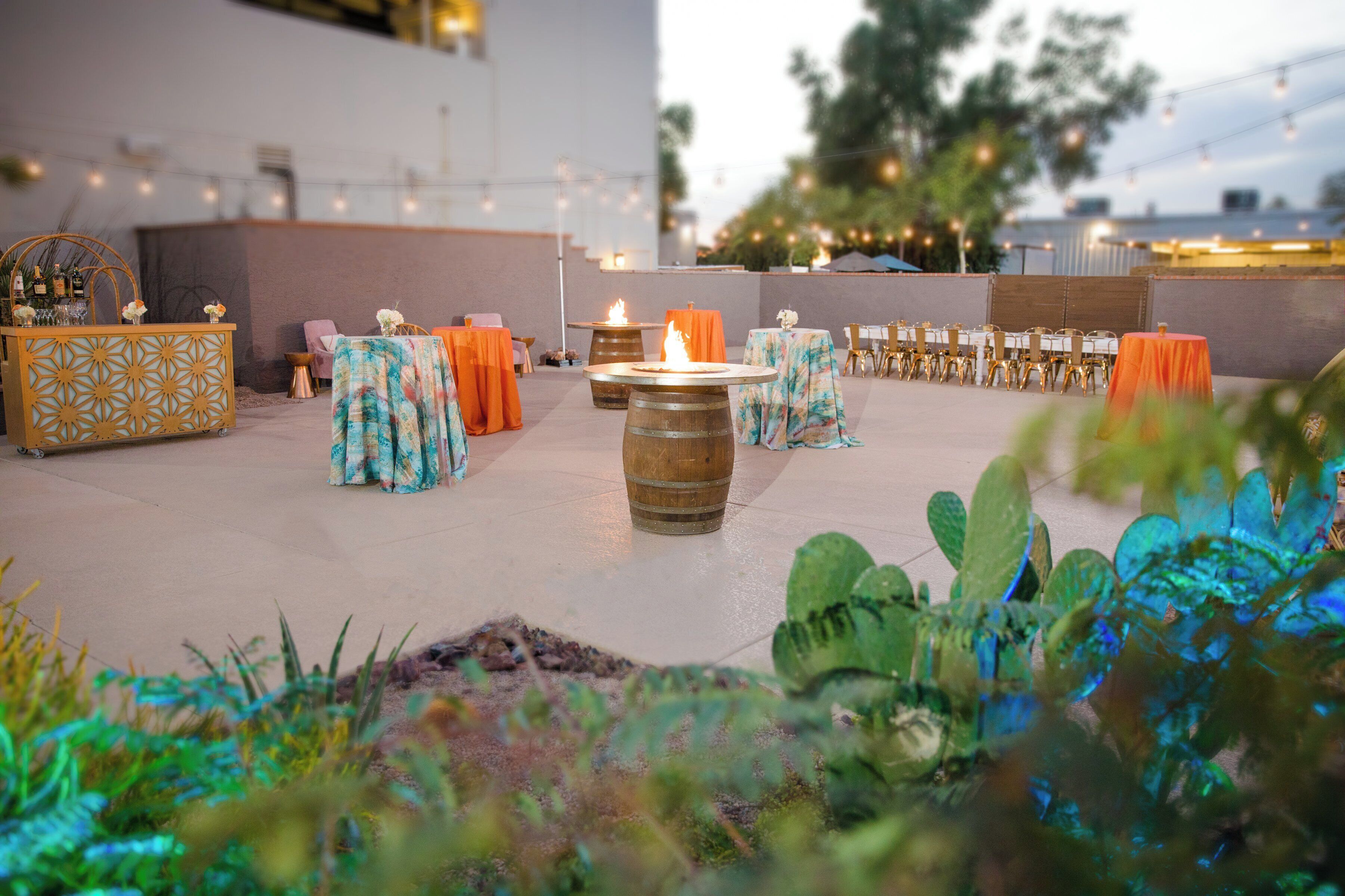 An outdoor patio area with tables and chairs, a bar, and decorative lighting.