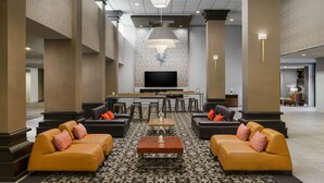 A spacious lobby with a central seating area, a bar, and a flat-screen TV on the wall. - Crowne Plaza Phoenix Airport - PHX by IHG (Phoenix)