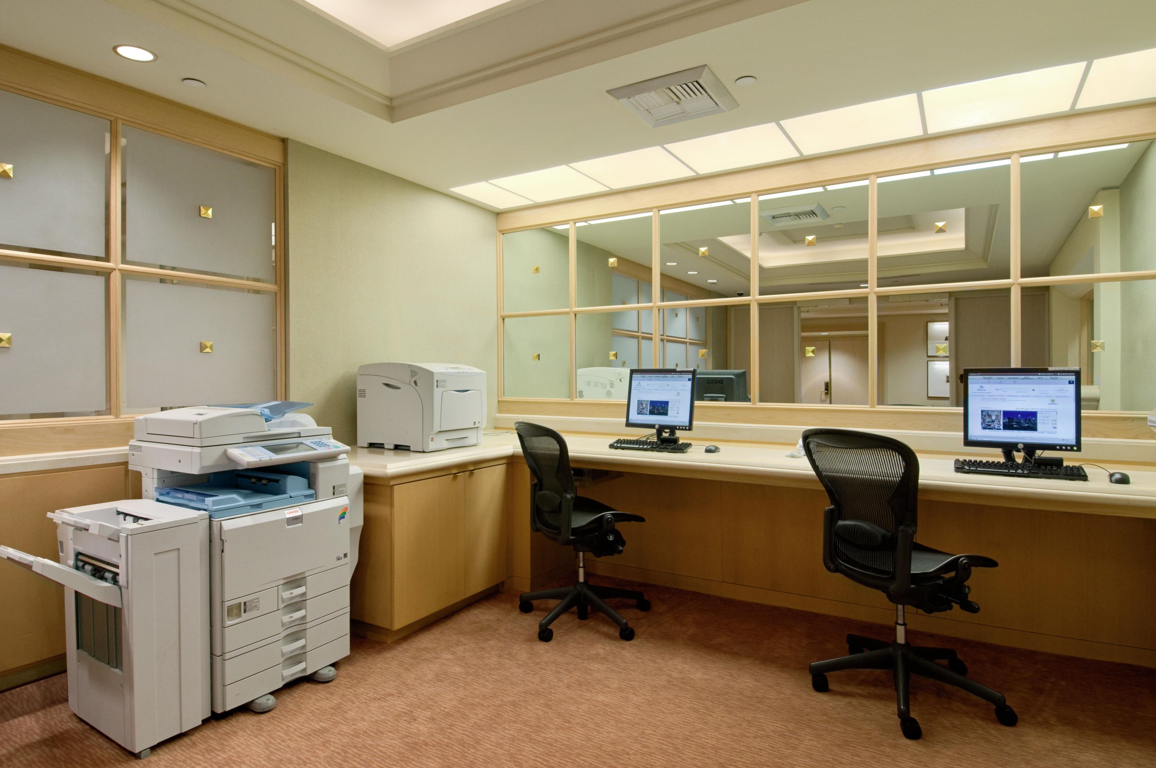 A modern office with two desks, chairs, and a printer.
