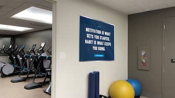 Une salle de sport équipée de tapis de course, de tapis de yoga et de ballons d’exercice.