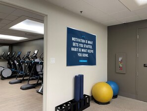 Un gimnasio con cintas de correr, colchonetas de yoga y pelotas de ejercicio.