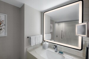 Een moderne badkamer met een grote spiegel, een witte marmeren countertop en een handdoekrek.