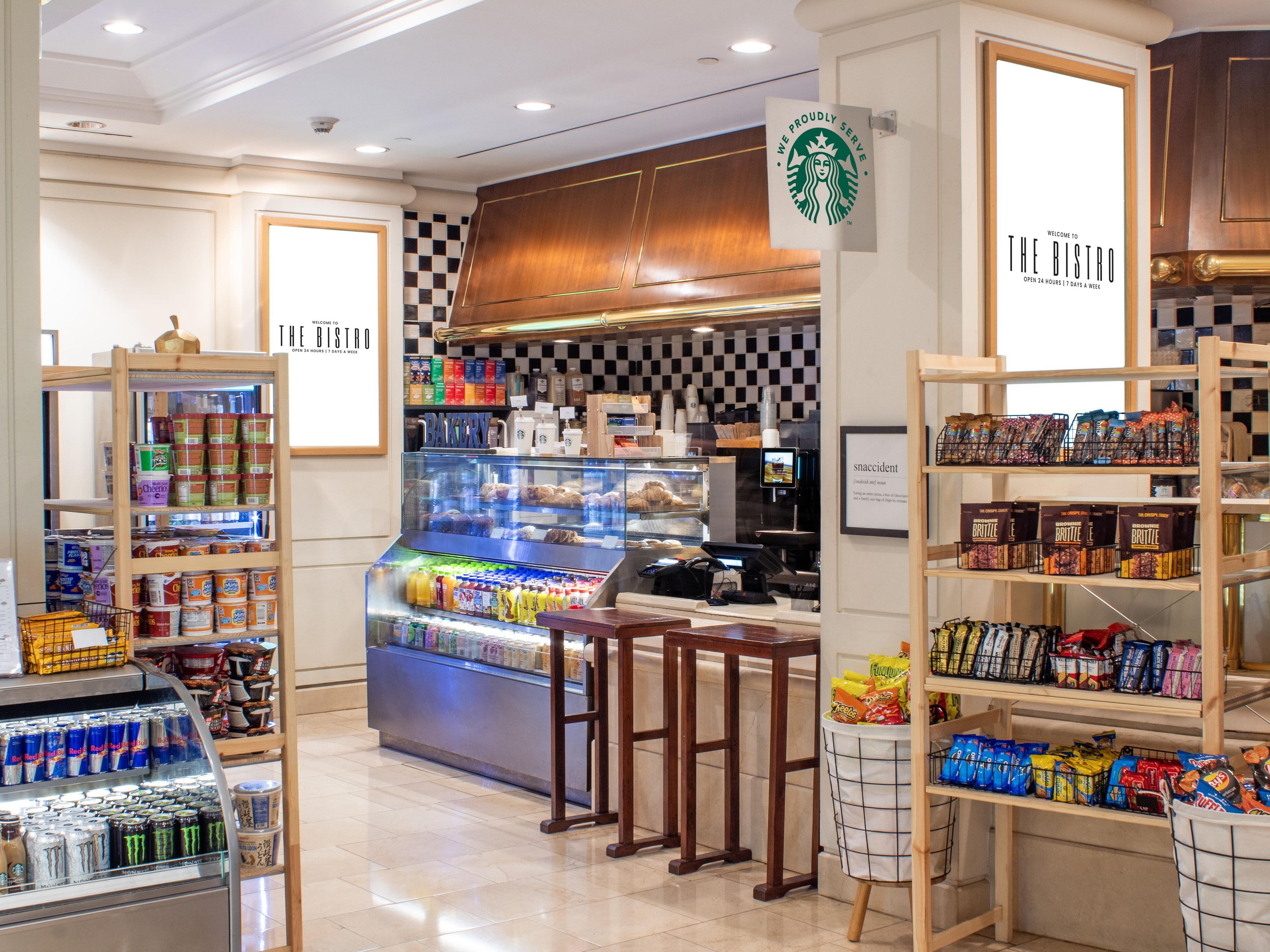 Een Starbucks bistro met een bakkerijpresentatie, een snackbalie en schappen gevuld met merkproducten.