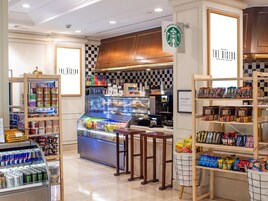 Een Starbucks bistro met een bakkerijpresentatie, een snackbalie en schappen gevuld met merkproducten.